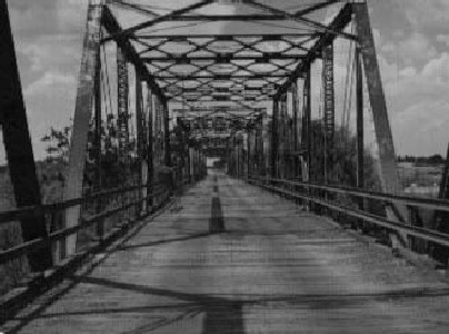 A rickety old bridge, rusty but picturesque, more than once maintaining her stately stance even though her old boards were awash in turbulent water and her tired girders bombarded with debris.